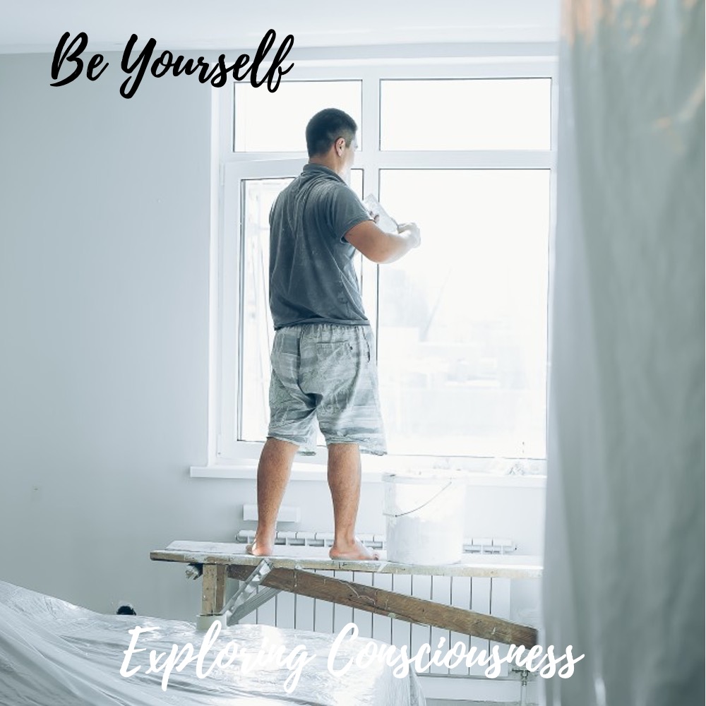 Man painting window with 'Be Yourself' text.