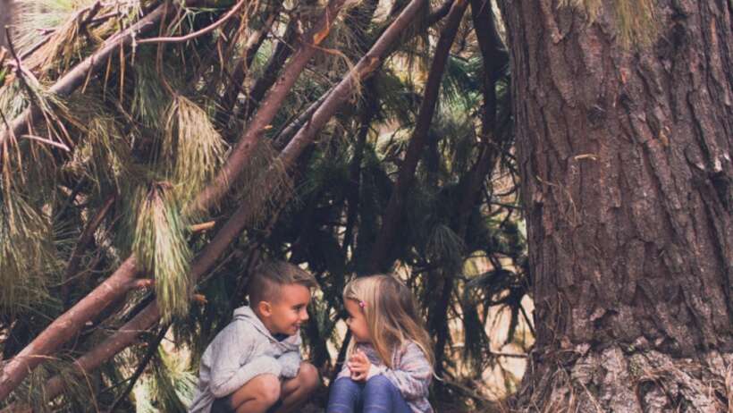 Children in woodland den, talking.