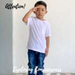 Boy in white tee saluting.