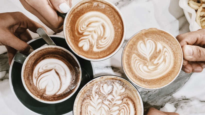 Four coffees with latte art on marble table