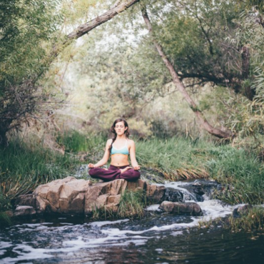 Woman meditating by stream in nature