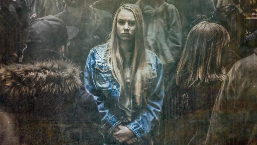Woman in denim jacket surrounded by people.
