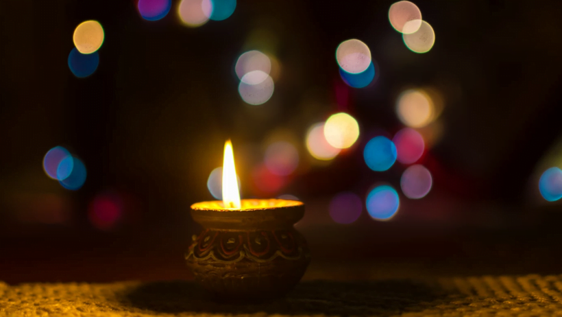 Lit diya with colourful bokeh in background