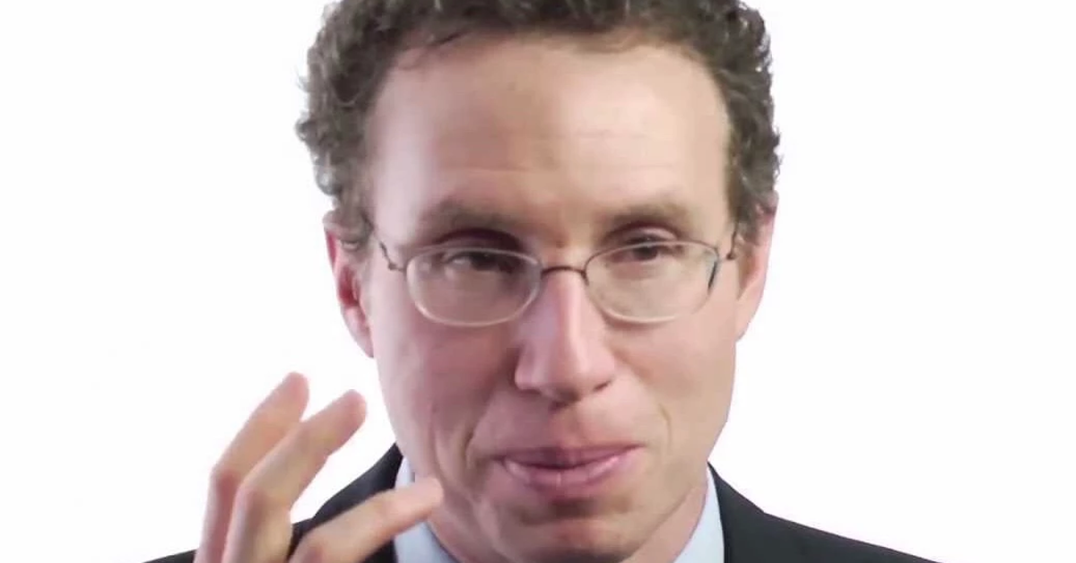 Man in glasses speaking to camera.