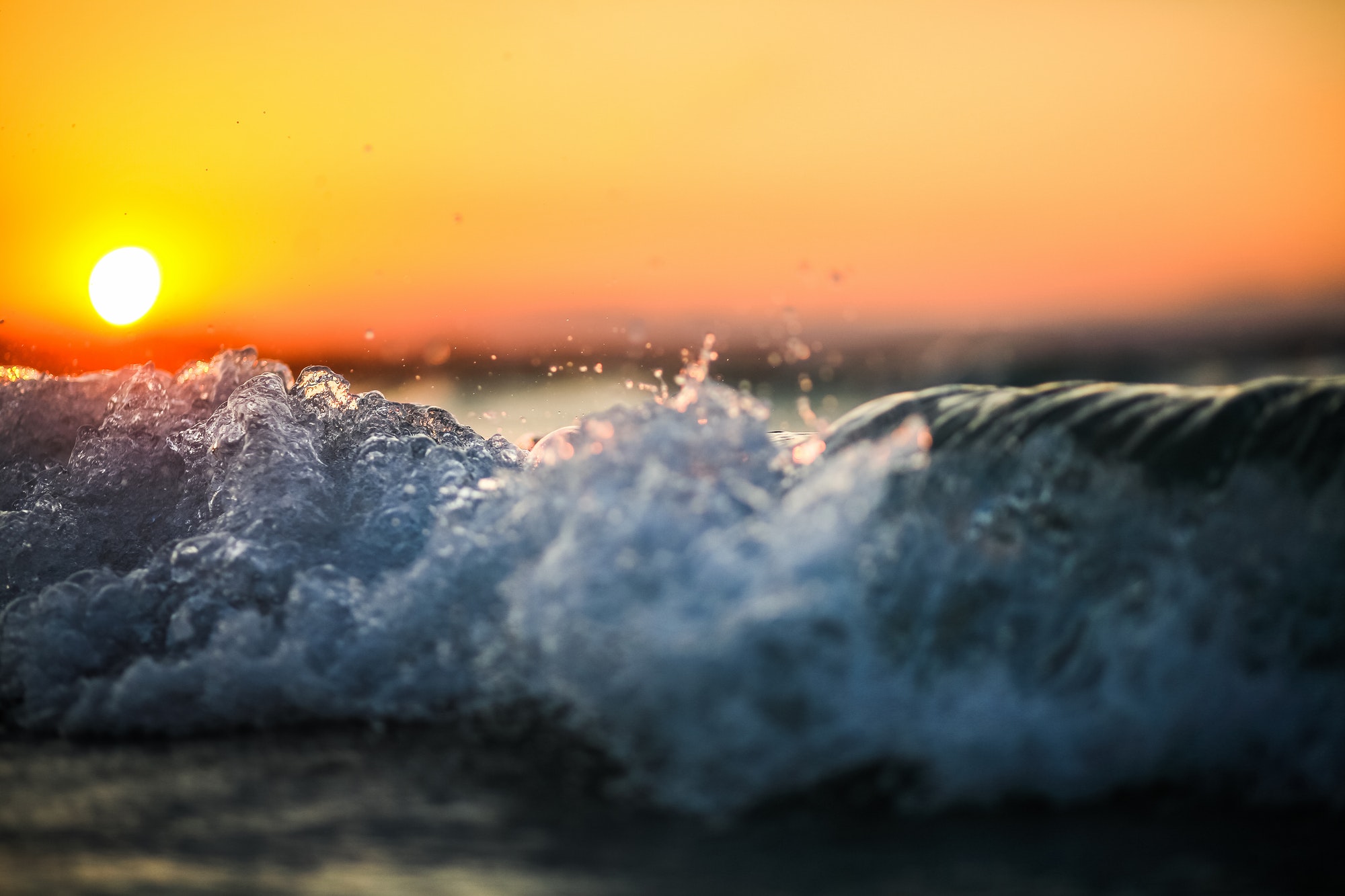 Waves crashing at sunset, golden sky.
