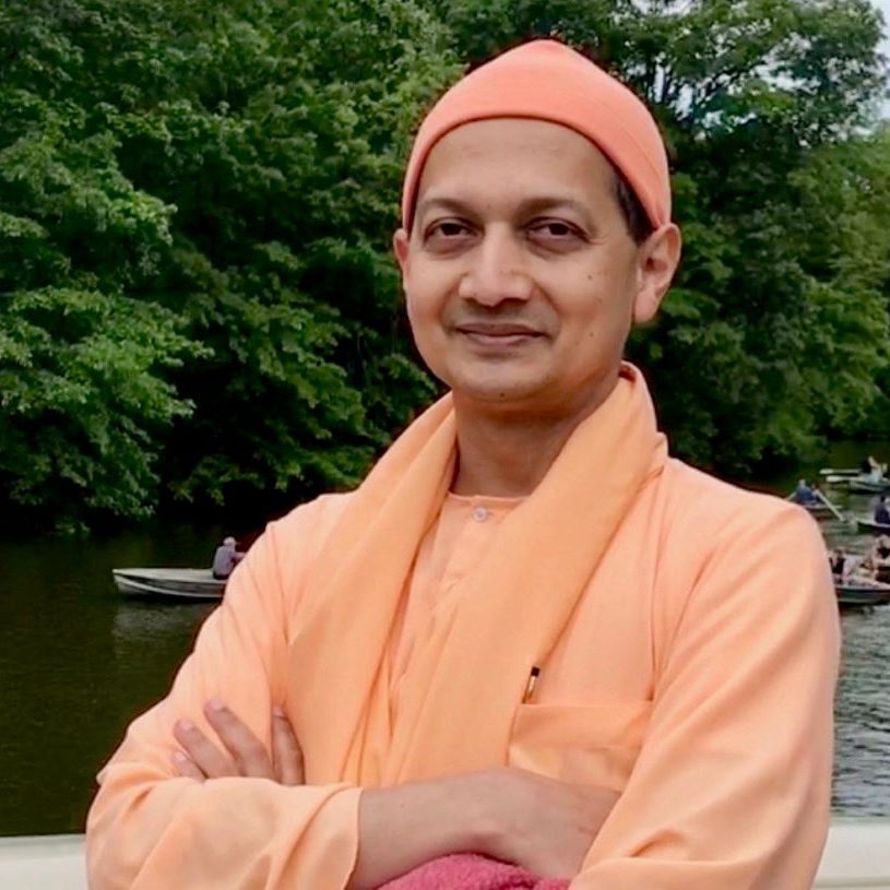 Man in orange robes by a river.